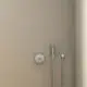 Brausearmatur der Marke Ideal Standard an einer hellen Wand, bestehend aus einer Handbrause mit Schlauch und einem Wand-Bedienpanel für die Wasserregulierung.